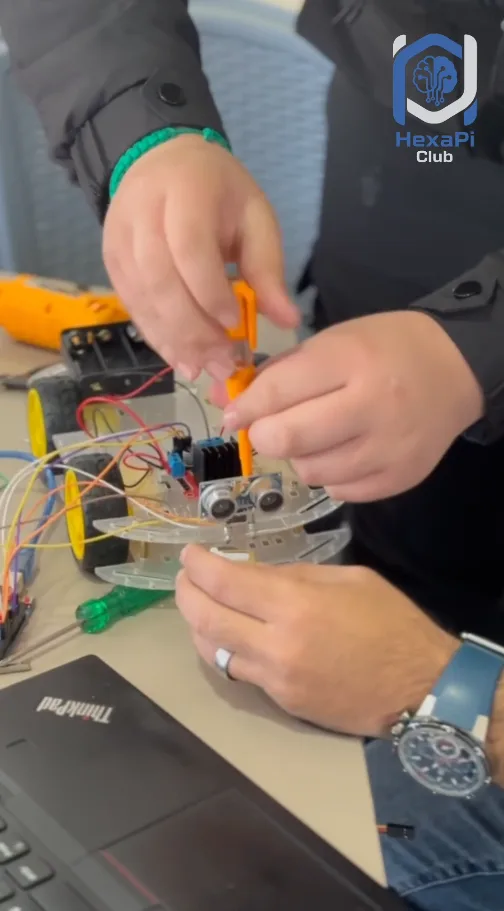 Hands wiring up a sensor-driven robot build